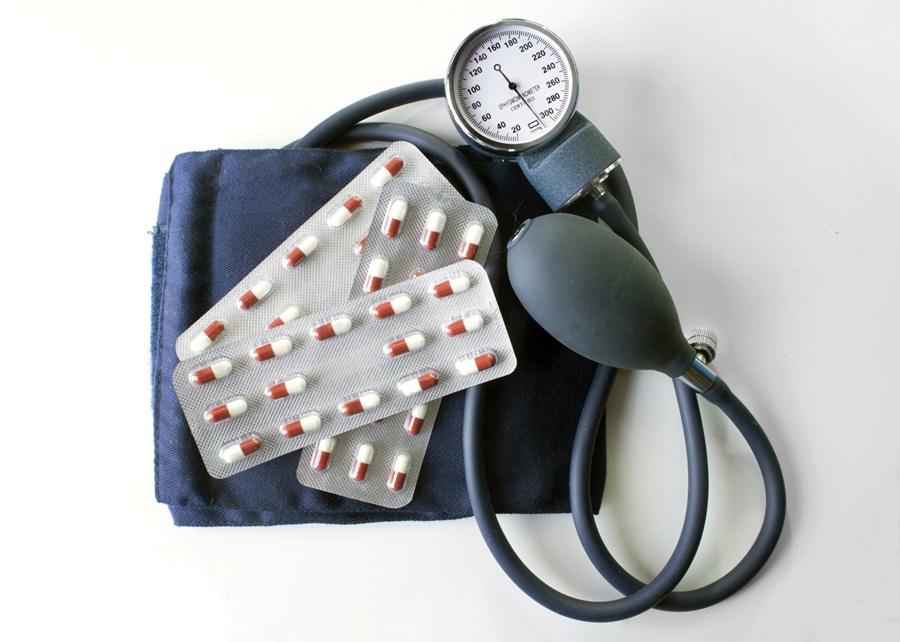 blood pressure cuff wrapped around blister pack of red and white pills