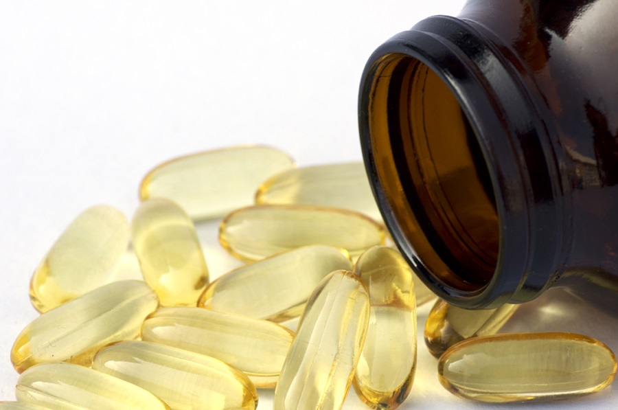yellow soft gel capsules spilling from a medication bottle