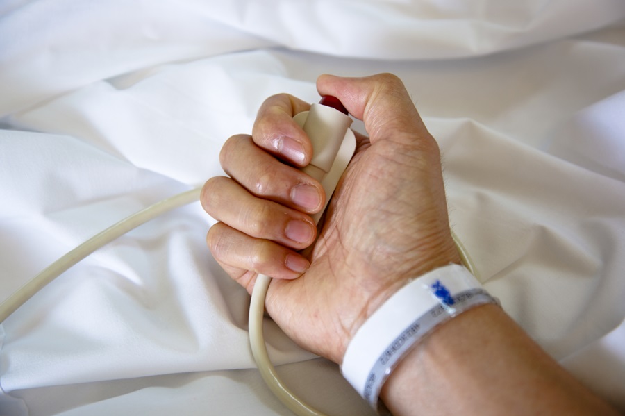 close-up of older adult hand gripping medication control button