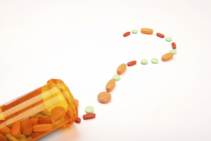 Stylish spilled pill bottle with pills in the form of a question mark